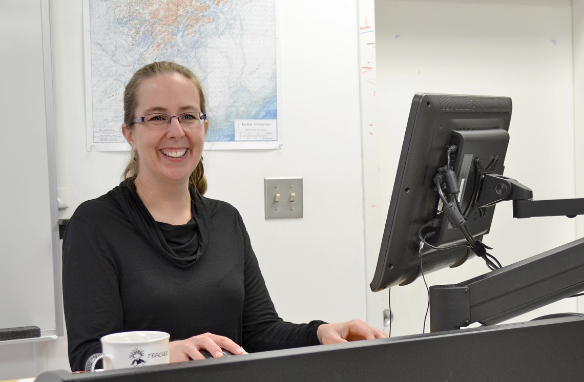 smiling woman standing at a computer workstation