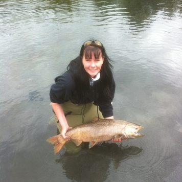 Woman standing in a river holding a salmon