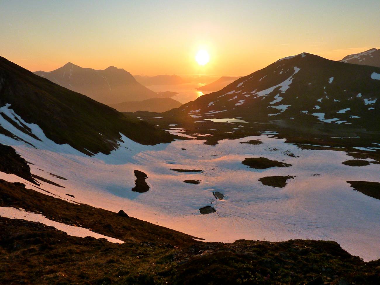 sun setting over a mountainous bay in alaska